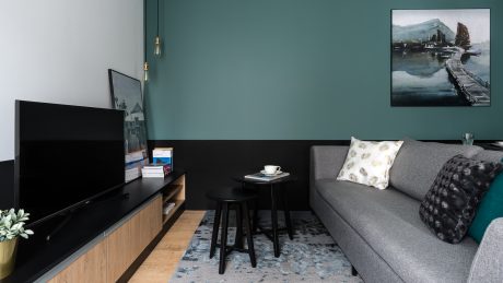 Cozy living room with gray sofa, black entertainment unit, and abstract artwork.