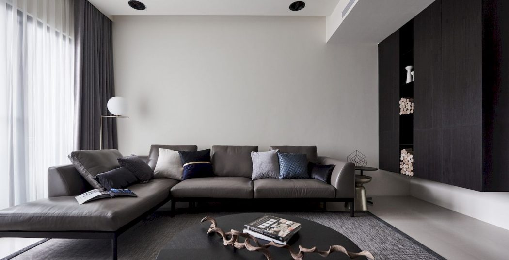 Minimal modern interior with gray sofa, hardwood floors, and recessed lighting.