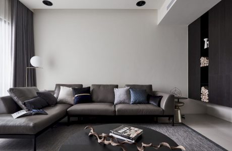 Minimal modern interior with gray sofa, hardwood floors, and recessed lighting.