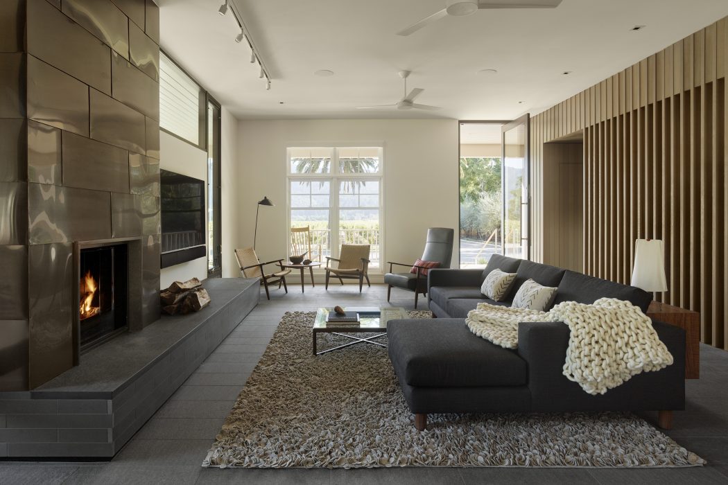 Modern living room with sleek fireplace, plush furnishings, and floor-to-ceiling windows offering scenic views.
