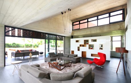 Spacious modern living room with high ceiling, glass walls, and eclectic furnishings.