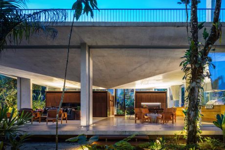 A modern tropical home with an open-concept living space, wooden furniture, and lush greenery.