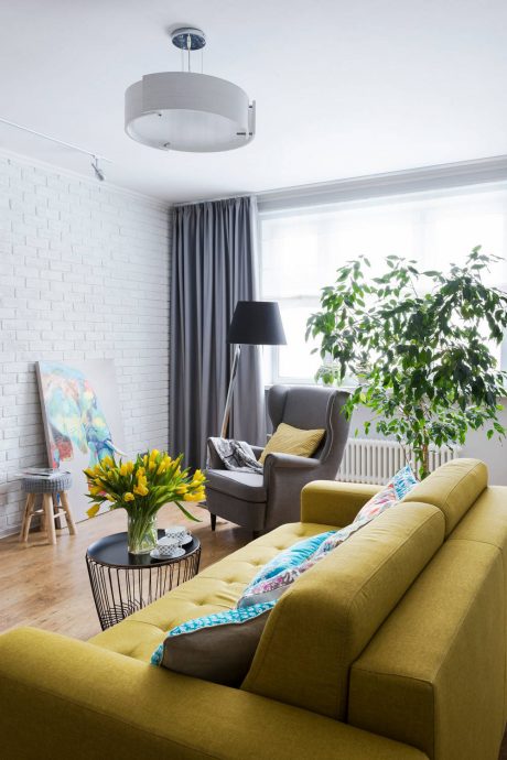 Bright, modern living room with yellow sofa, potted plant, and abstract artwork.