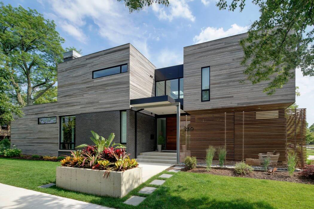A modern, two-story home with a sleek, wood-paneled exterior and a lush, landscaped garden.
