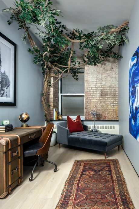 Rustic loft-style space with natural branch decor, vintage trunk, and patterned rug.
