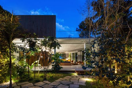 Contemporary tropical home with open-plan design, lush landscaping, and warm lighting.
