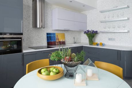 A modern kitchen with sleek gray and white cabinetry, complemented by a colorful succulent arrangement and minimalist decor.