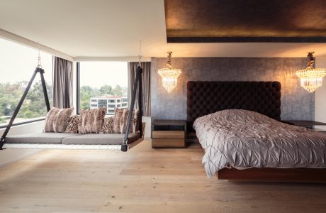 Spacious bedroom with plush, tufted headboard, crystal chandeliers, and a hanging swing.