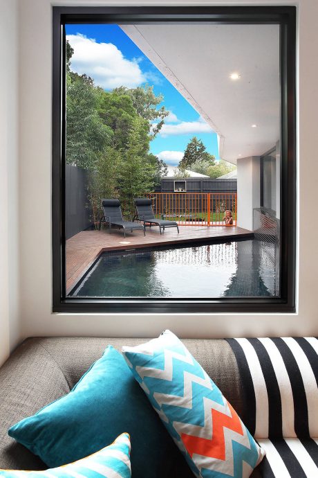 Cozy living space with a modern minimalist design, featuring a sleek pool and lush outdoor views.