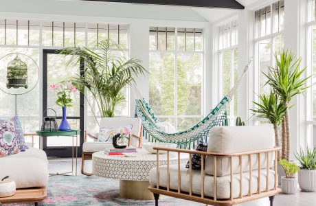 Bright, airy sunroom showcases modern furniture, lush greenery, and open windows.