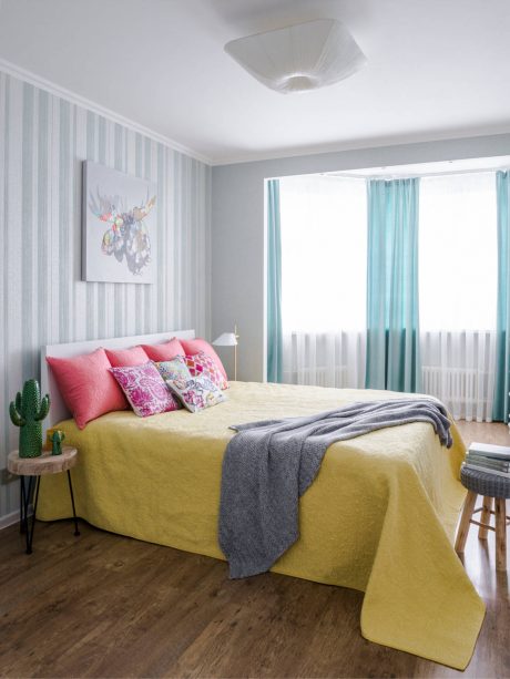 A welcoming bedroom with striped walls, colorful accents, and modern furnishings.