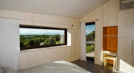 Bright, minimalist bedroom with large window overlooking verdant countryside.