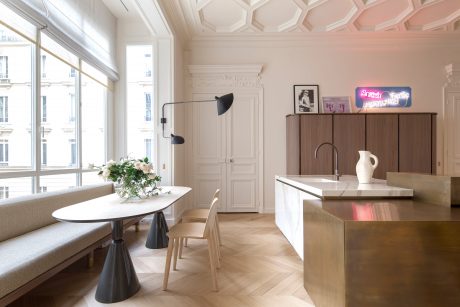 Elegant parisian apartment with ornate ceiling, sleek kitchen, and cozy seating area.