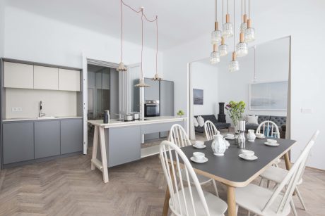 An open-plan contemporary kitchen and dining area with sleek gray cabinetry, a central island, and modern pendant lighting.