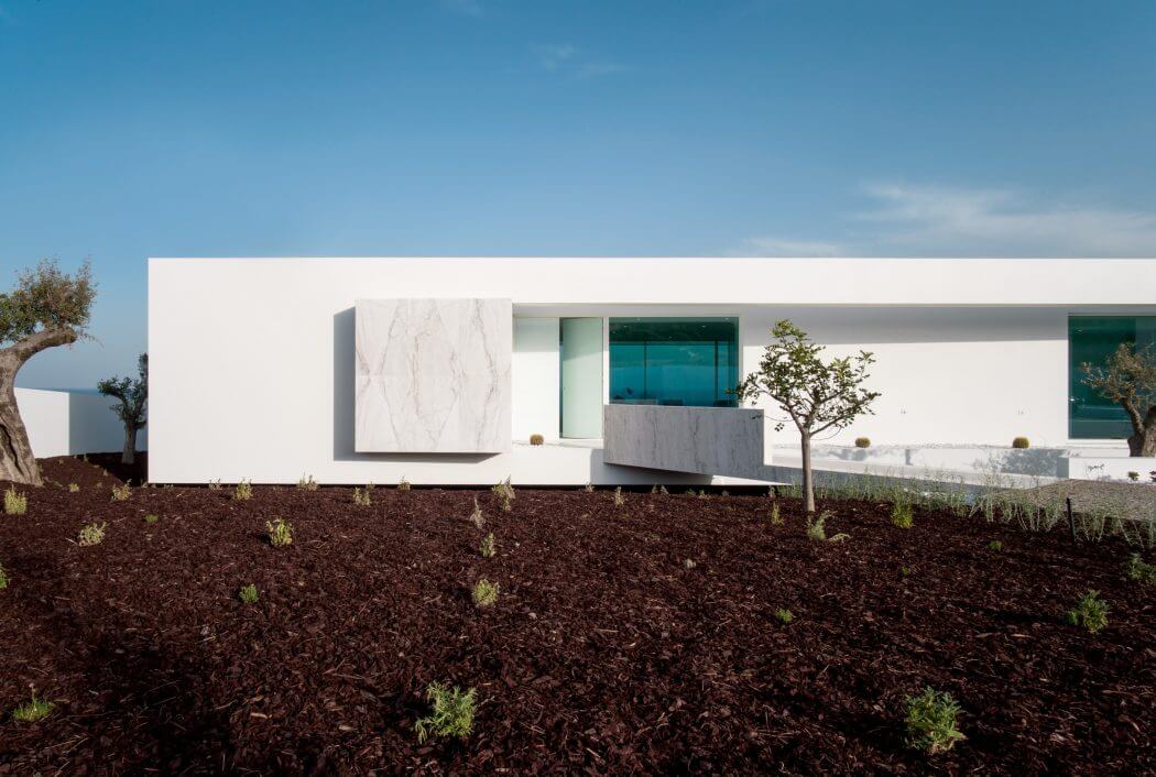Modern minimalist residence with clean lines, large windows, and surrounding vegetation.