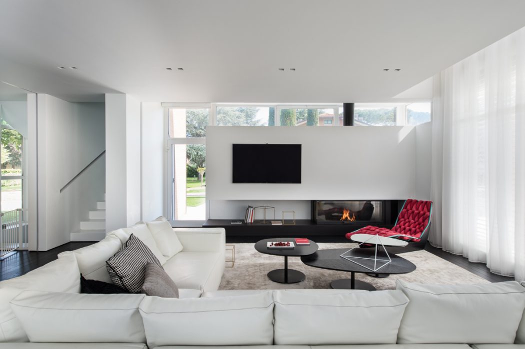 Sleek, modern living room with fireplace, large windows, and bold red accent chair.