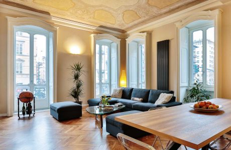 Ornate, high-ceilinged room with arched windows, decorative molding, and modern furnishings.