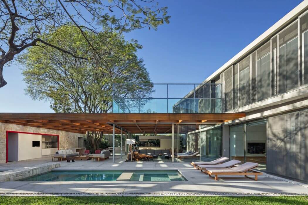 Modern glass and concrete architecture with a rectangular pool and lounge area.