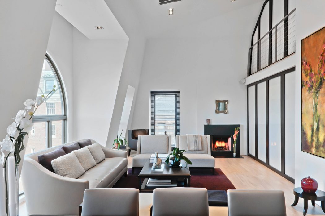 Bright, modern living room with large windows, plush seating, and a fireplace.
