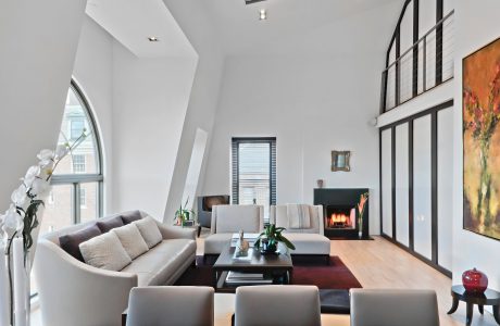 Bright, modern living room with large windows, plush seating, and a fireplace.