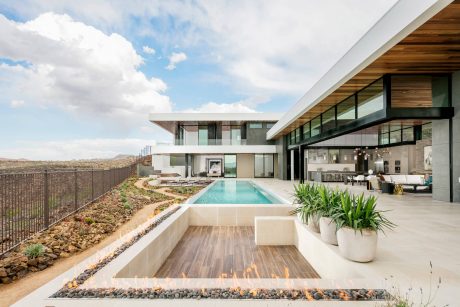 Sleek modern home with a pool, wood-accented exterior, and a fire feature on the patio.