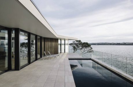 A modern waterfront home with sleek architectural features and an infinity pool.