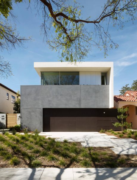 Modern, minimalist house with a geometric facade, large windows, and a contrasting garage door.