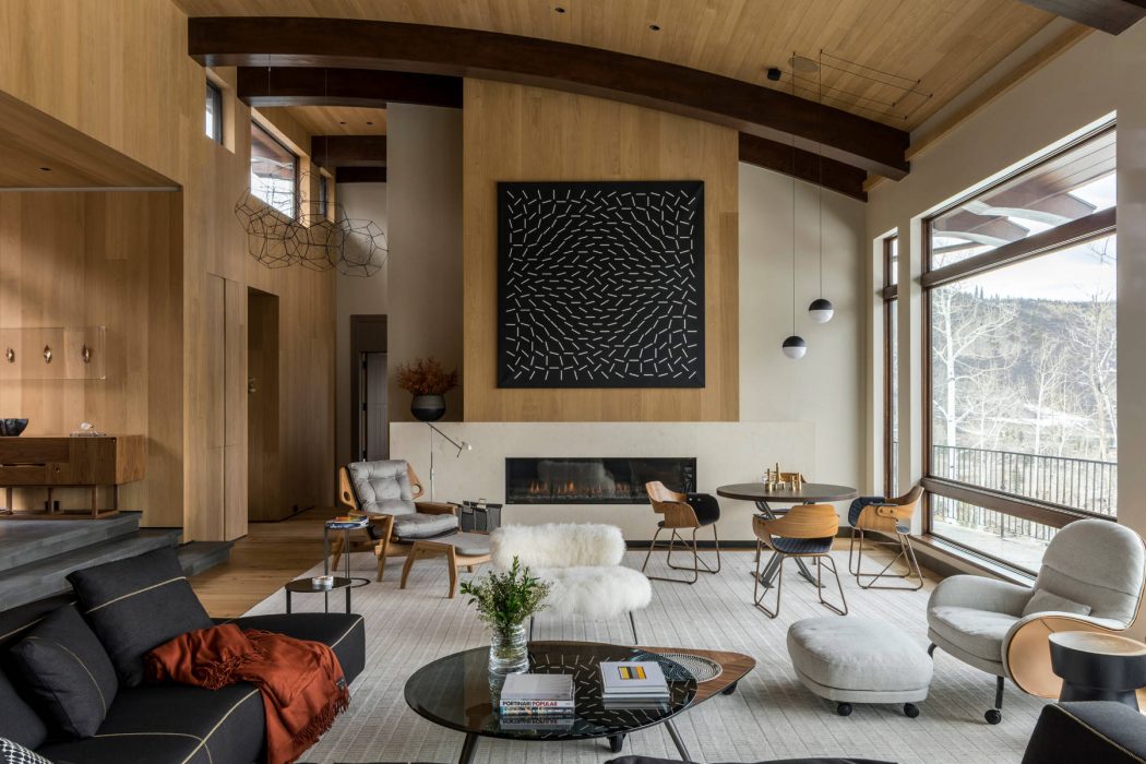 A modern, open-concept living space with wood beams, a fireplace, and eclectic furnishings.