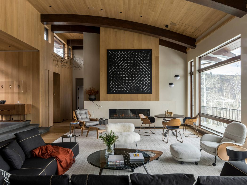 A modern, open-concept living space with wood beams, a fireplace, and eclectic furnishings.