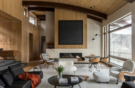 A modern, open-concept living space with wood beams, a fireplace, and eclectic furnishings.