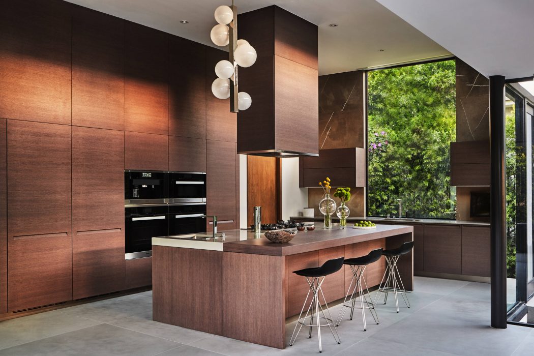 Sleek, modern kitchen design with dark wood cabinetry, marble countertops, and pendant lighting.