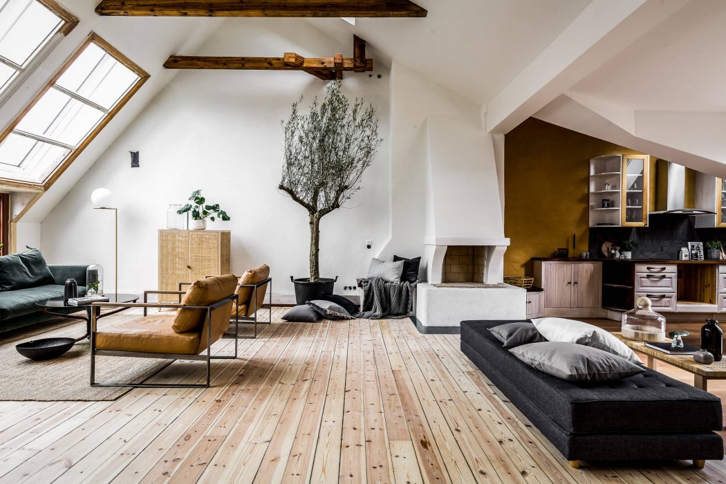 Cozy attic living room with rustic wooden beams, modern furniture, and natural plant decor.