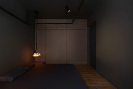 Dimly lit modern bedroom with minimalist design and hanging pendant lights.