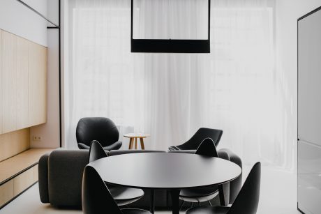 Modern, minimalist living room with circular dining table and black leather chairs.