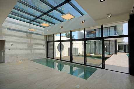 Expansive glass atrium with minimalist interior design, sleek pool, and natural lighting.