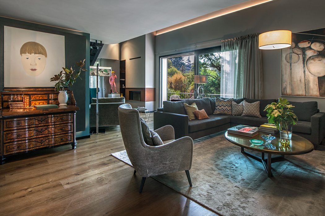 Elegant living room with modern furniture, ornate dresser, and large window overlooking nature.