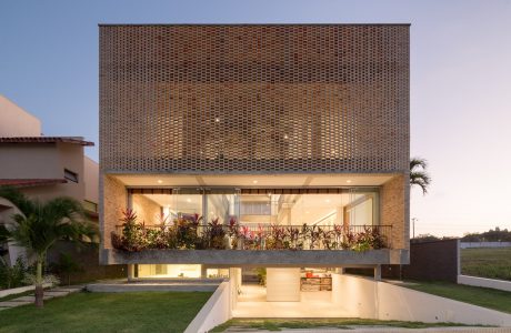 Striking modern architecture with intricate brick facade, expansive glass walls, and lush greenery.