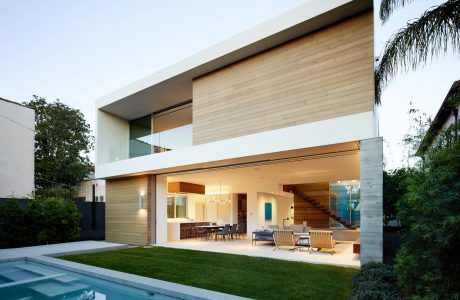 Modern, minimalist home with clean lines, wood siding, and large glass windows overlooking a pool.