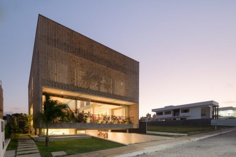 Contemporary architectural design with perforated facade, balcony, and landscape.
