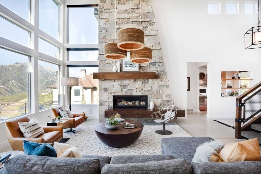 Spacious living room with stone fireplace, wood beam accents, and modern pendant lights.