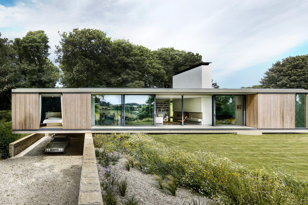 A modern, low-profile, single-story residence with large glass windows and a wooden exterior.