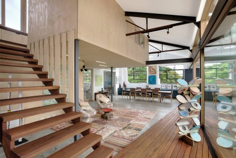 A modern, open-concept interior with wooden stairs, beams, and an eclectic mix of furnishings.