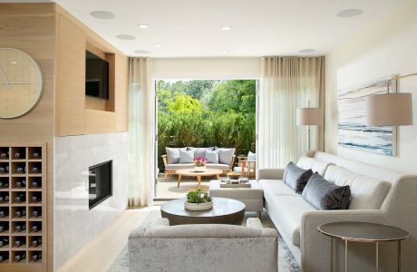 Elegant living room with floor-to-ceiling windows offering scenic outdoor views, warm wood accents.