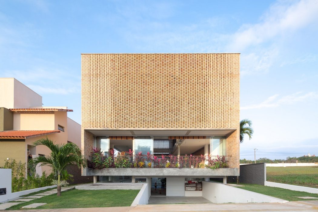 Striking modern architecture featuring a perforated wooden facade and lush greenery.