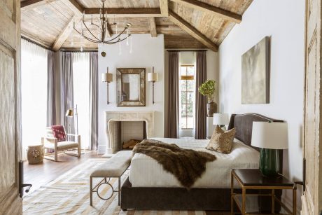 Rustic bedroom with vaulted wood ceiling, fireplace, and cozy furnishings.