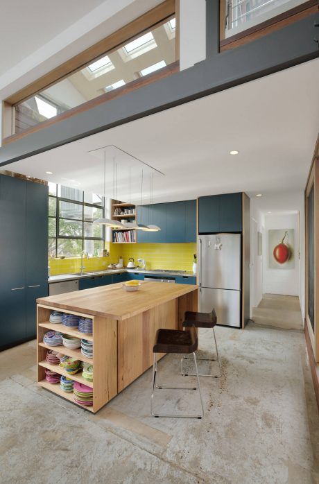 Bright, modern kitchen with wood accents, shelving, and vibrant yellow backsplash.