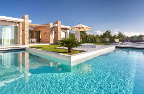 Luxurious modern villa with sleek pool, lush landscaping, and warm stone accents.