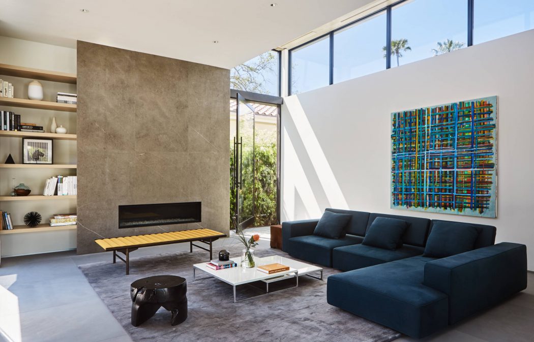Sleek, modern living room with floor-to-ceiling windows, concrete fireplace, and vibrant artwork.