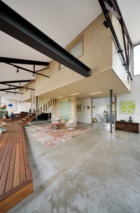 An open-concept interior with high ceilings, exposed beams, and a mix of wood and concrete elements.