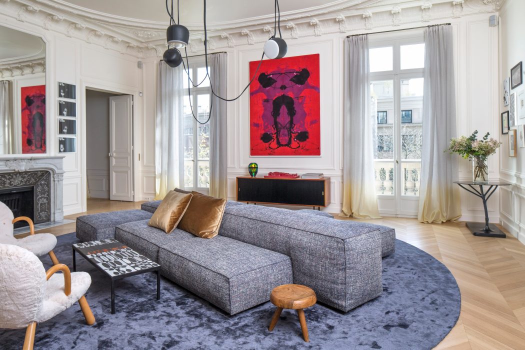 Elegant living room with ornate architectural details, modern furnishings, and vibrant artwork.